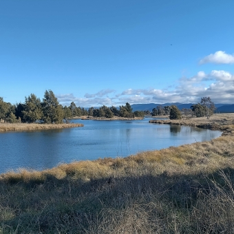 Vast Blue, West Belconnen Pond, Dunlop, with a meandering lake reflecting the blue of the sky and dry-green grass surrounding