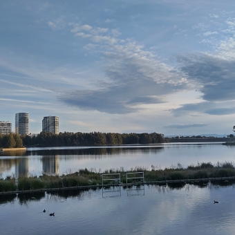 Yerrabi Pond, Amaroo, with clear water in from reflecting high rise buildings on the left and wispy clouds in the sky on the right