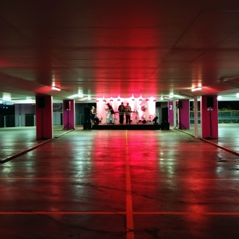 Parramatta Lanes, Eat Street Carpark, Parramatta, with an empty carpark lit with eerie red lights and a stage at the other end