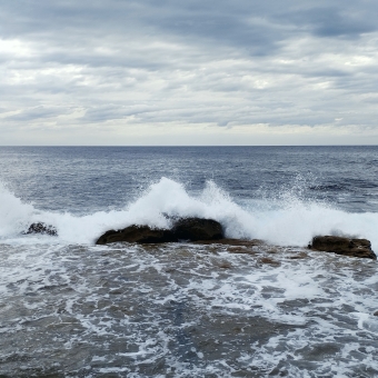 Overflowing Shelf, Boora Point Trail, with white water-spray over rocks in the middle, with wavy ocean and rolling clouds to the horizon