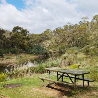 The Nowhere Table, Blue Tiles Picnic Area, Molonglo Gorge Nature Reserve, with a park bench surrounded by grass and a lake and only trees into the distance