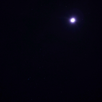 The Nights Sky, with a crescent moon glowing in the top-right corner and many stars scattered like grains of rice across the sky